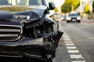 samochód z uszkodzoną wskutek stłuczki maską stoi na jezdni